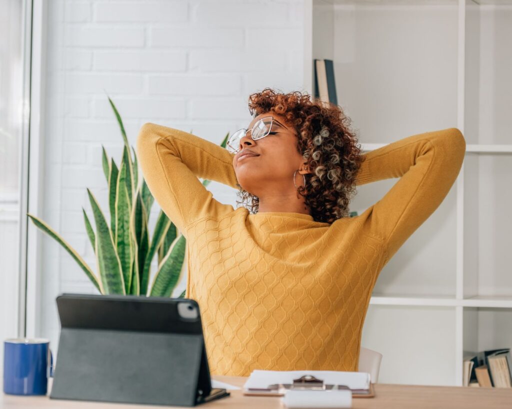 Midlife professional woman at her desk taking a restorative pause, illustrating menopause at work, career strategy, and sustainable leadership performance.