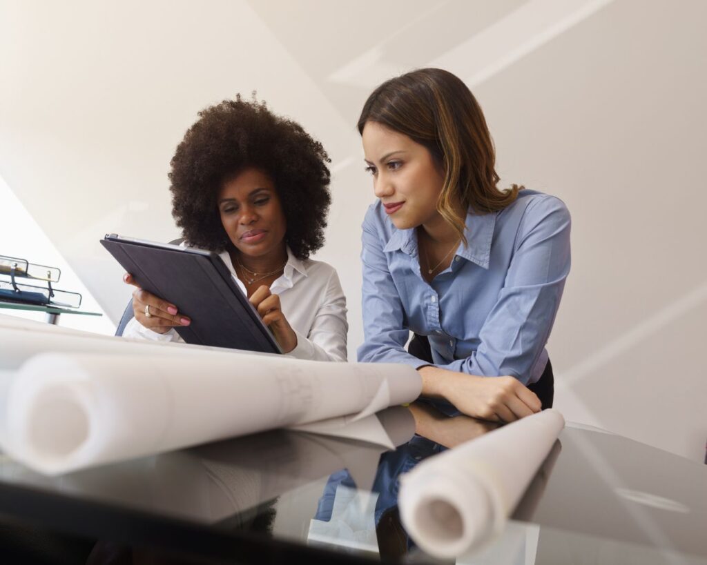 Two women in a workplace reviewing plans together, illustrating midlife workplace communication, leadership visibility, and professional self-advocacy.