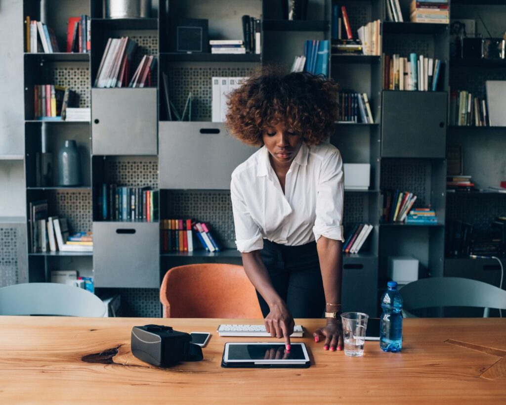 Woman thoughtfully using a tablet at a desk in a modern office, reflecting on choices and new directions.