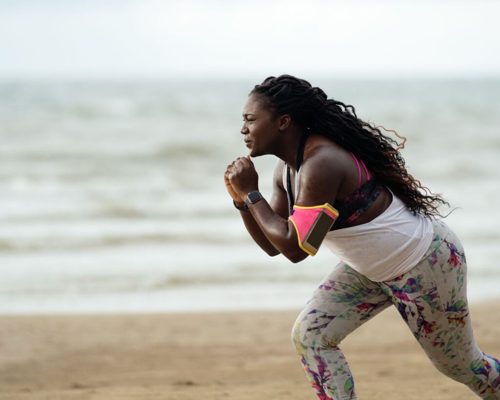 Woman exercising on the beach with a focused expression, representing self-trust, awareness, and listening to yourself.